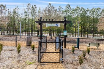 A sign for a dog park is displayed on a fence.